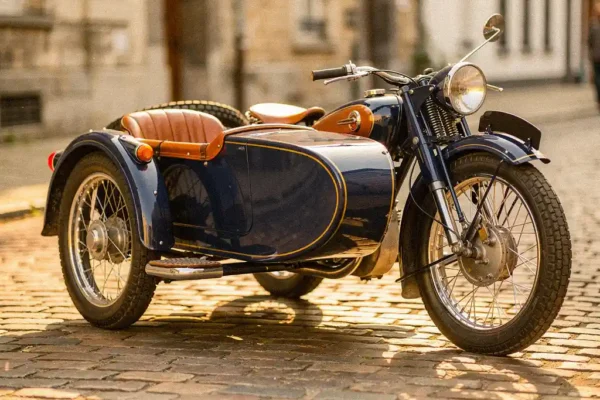 Glanzende vintage motorfiets met zijspan op Belgische kasseienstraat, badend in warm middagzonlicht met chromen details.
